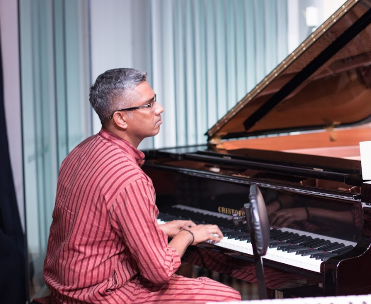 Swaram Studio music teacher demonstrating Indian raga techniques with chords on a piano in music studio
